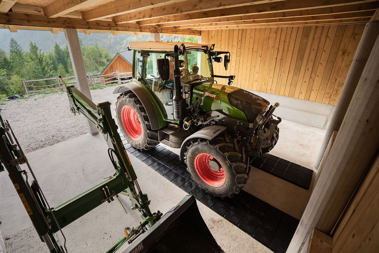 Traktor parkiran v garaži na pohodne plošče, ki ščitijo betonska tla.