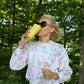 Tanja Skaza v športni opravi pije iz rumenega trajnostnega kozarca Skaza z motivom solarnega pleksusa med sprehodom po gozdu, obdana z zelenjem in jutranjo svetlobo.