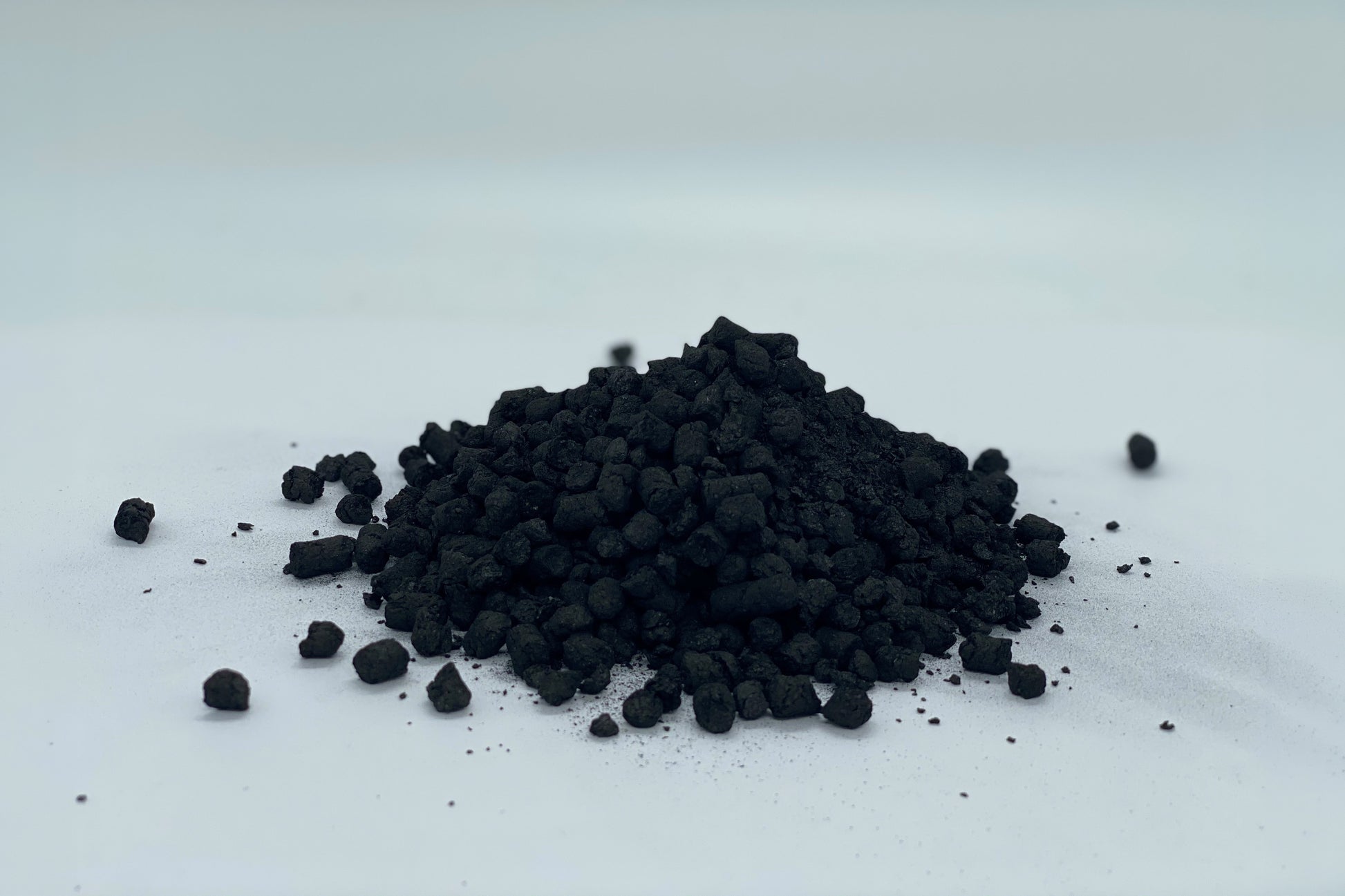 Granule Biocharja na beli podlagi, pripravljene za uporabo pri izboljšanju rodovitnosti tal in zadrževanju hranil.