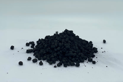 Granule Biocharja na beli podlagi, pripravljene za uporabo pri izboljšanju rodovitnosti tal in zadrževanju hranil.