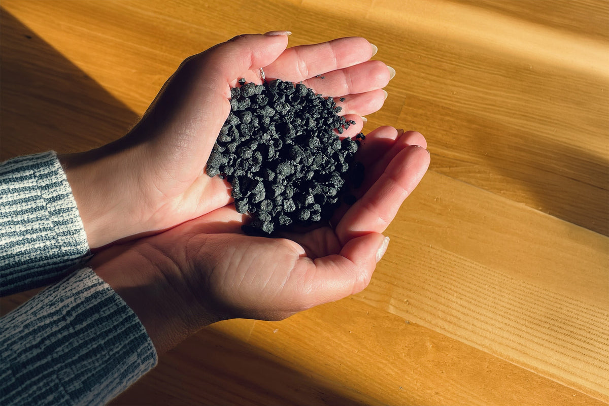Biochar v dlaneh prikazuje strukturo poroznih granulatov za izboljšanje kakovosti zemlje in rast rastlin.