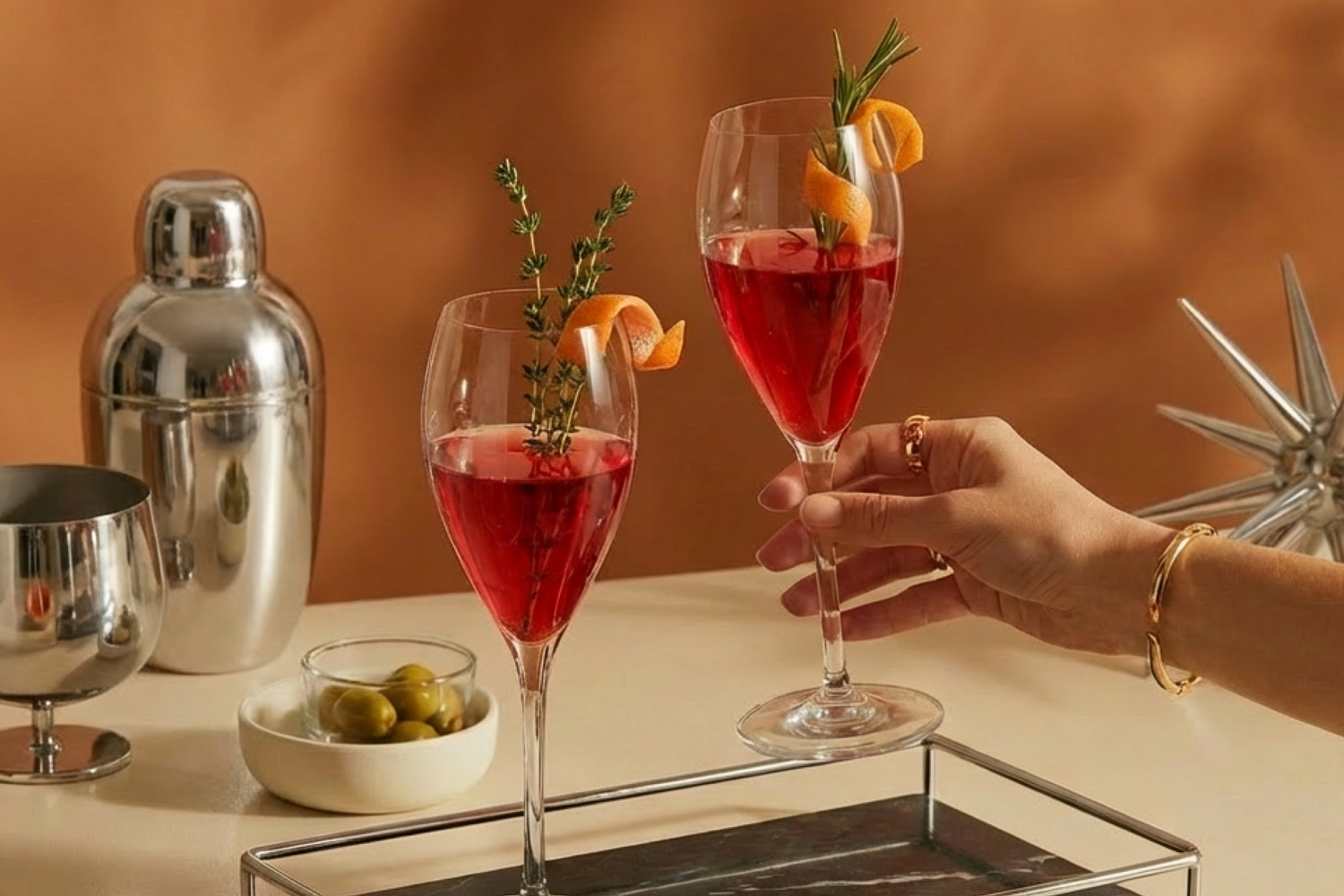 Koktajl v kozarcih za šampanjec z dekoracijo pomaranče in zelišč.