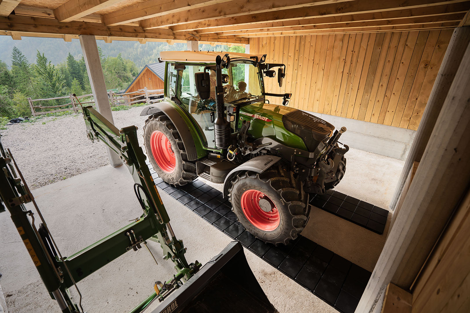 Traktor parkiran v garaži na pohodne plošče, ki ščitijo betonska tla.